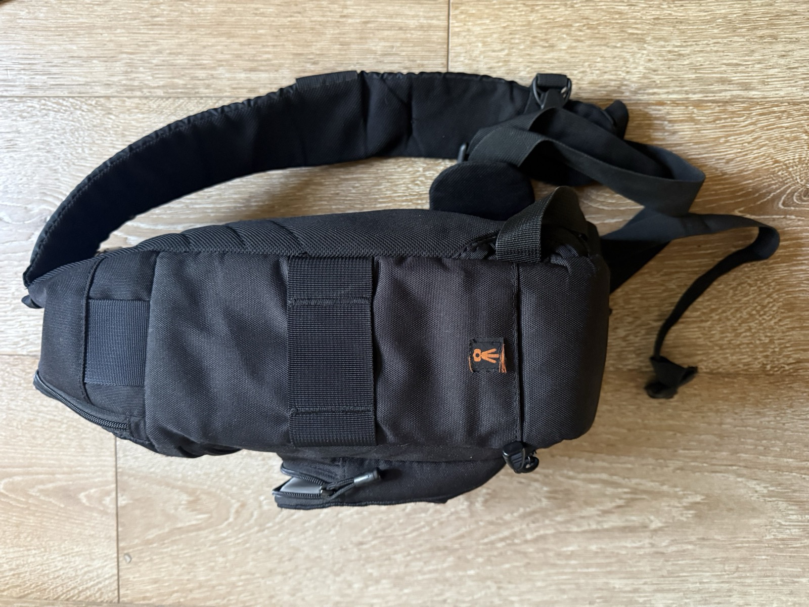 Rear view of the Lowepro Slingshot 202 AW showing the single padded sling shoulder strap and thin webbing waist stabilizer strap