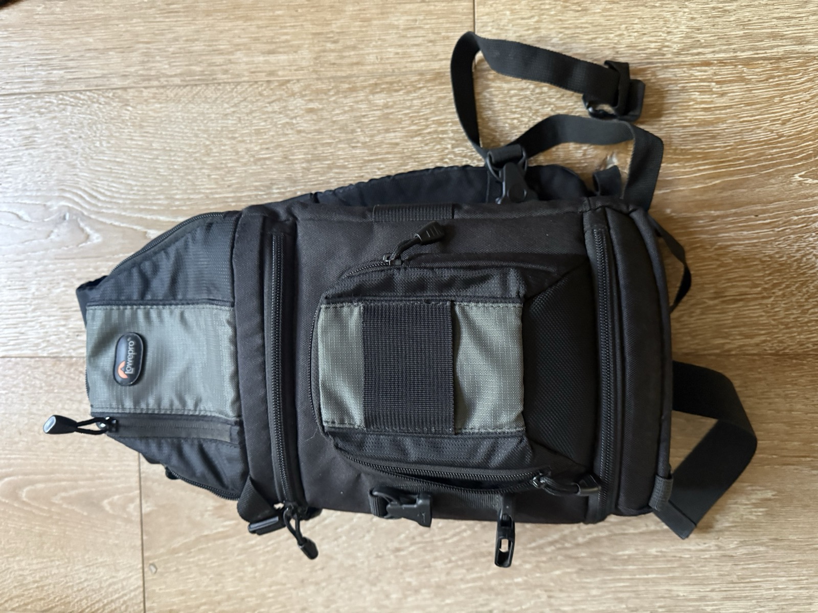 Lowepro Slingshot 202 AW seen from above showing the front accessory pocket, side mesh pockets, and single sling shoulder strap in classic 2010s Lowepro dark-gray-and-black colorway